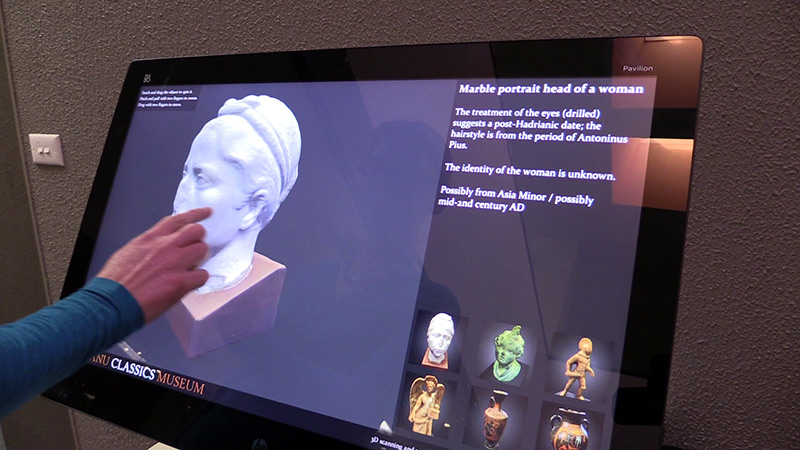 Photo of a woman using a touchscreen exhibit of 3D scans